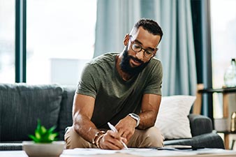 Man sitting on the sofa at home, making notes