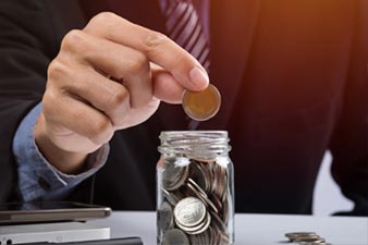 Man putting a coin into a jar full of loose change