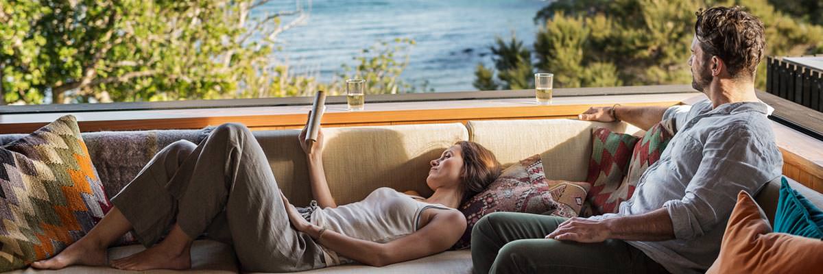 Couple relaxing at the bach, reading and looking out at the view