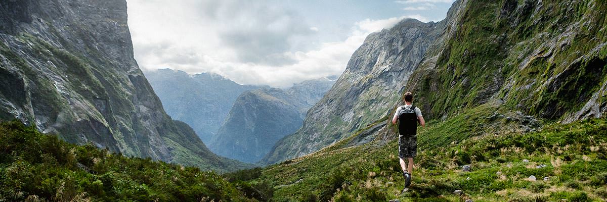 Tramper looking across a steep valley in the Fiordland National Park to the Southern Alps beyond