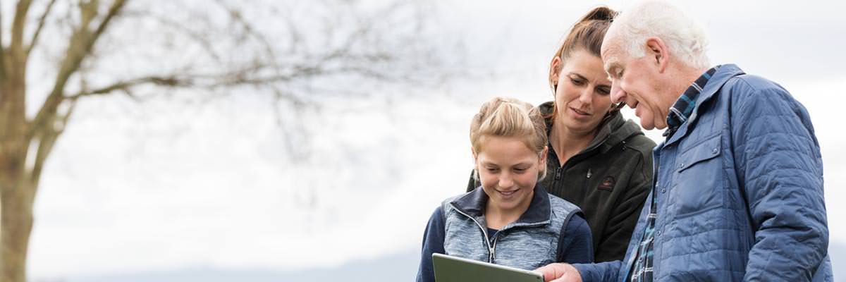 Three generations - grandfather, mother, daughter - looking at an iPad together