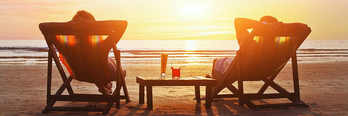 Couple relaxing in deckchairs on the beach, watching the sunset