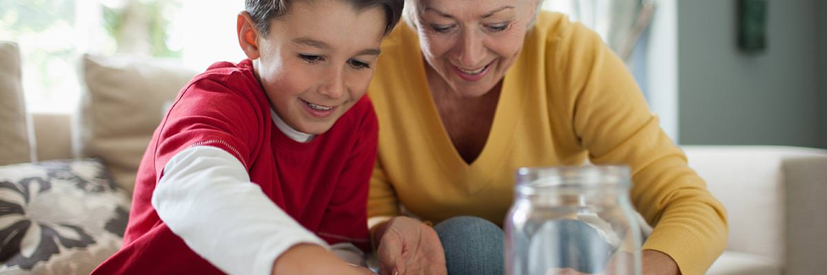 Grandmother and grandson counting money stored in a savings jar