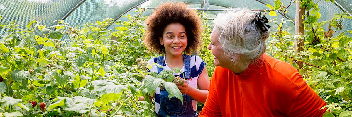 Woman working with teenager in community garden