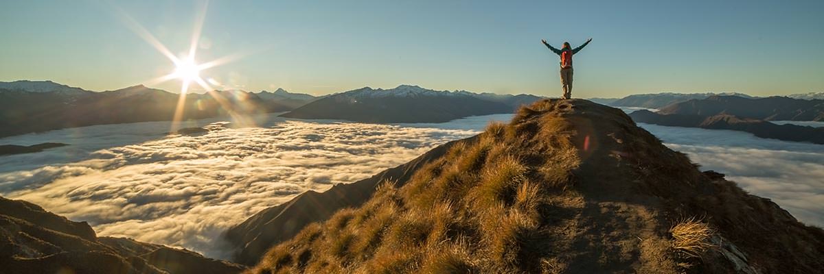 Woman standing on top of a mountain watching the sunrise