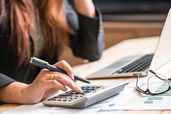 Woman working with calculator, pen, laptop and spreadsheets
