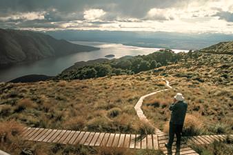 Man standing at the crossroads of two walking tracks, deciding which way to go
