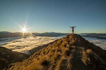 Woman standing on top of a mountain watching the sunrise