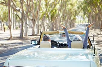Retired couple in an open-topped sports car, speeding along a country road