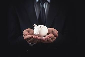 Man in a suit cradling a piggy bank in his hands